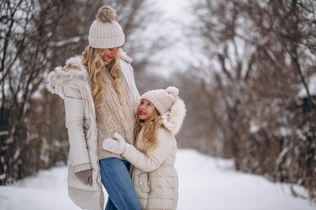 Mother with daughter walking together in a winter park