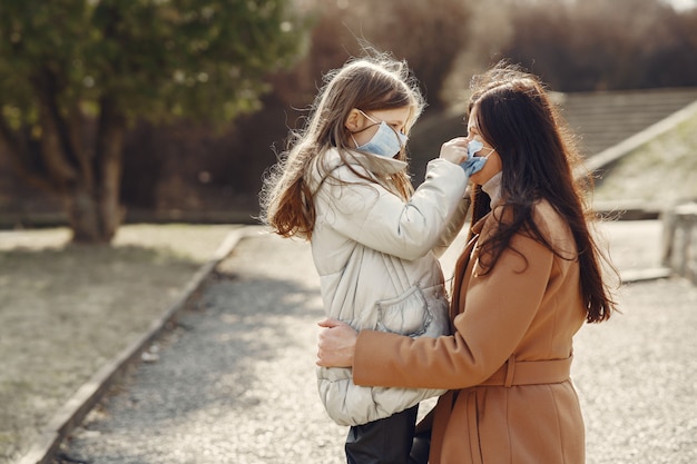 Free photo mother with daughter walks outside in masks