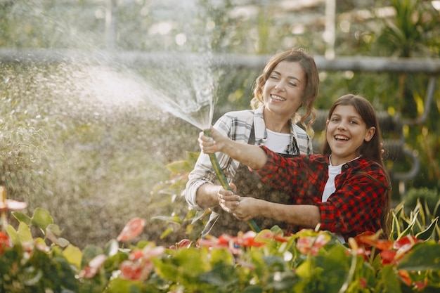 Free photo mother with daughter. workers with flowerpoots. people pours flowers