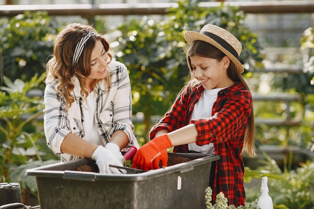 Free photo mother with daughter. workers with flowerpoots. woman transplanting plant a into a new pot