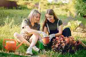 Foto gratuita la madre con una figlia lavora in un giardino vicino alla casa