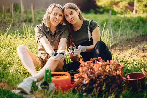 Mother with a daughter works in a garden near the house