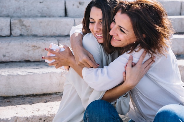 mother with gift hugging woman