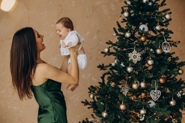 クリスマスツリーのそばに彼女の赤ん坊の娘と母