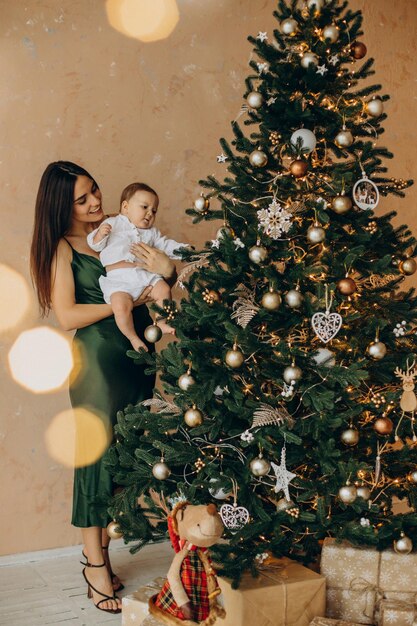 크리스마스 트리 옆에 그녀의 아기 딸과 함께 어머니