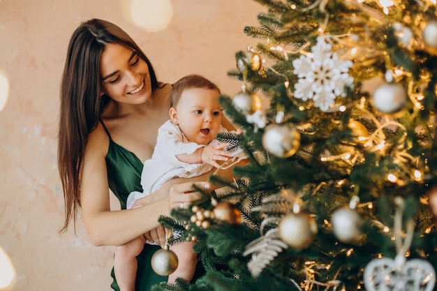Mother with her baby daughter by the christmas tree