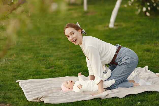 그녀의 아기와 함께 어머니는 여름 정원에서 시간을 보내고