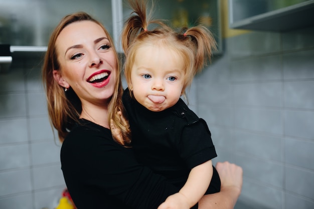 Mother with her daughter in arms and the girl with tongue out