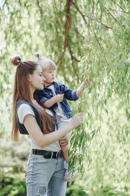 木の背景と腕の中で彼女の娘を持つ母親