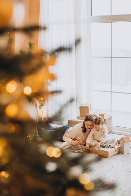 Mother with her daughter packing christmas presents and having fun