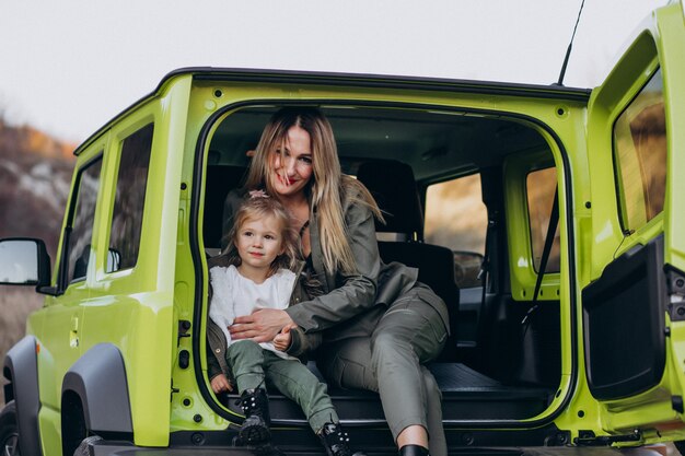 Mother with her little daugher sitting in the back of the car