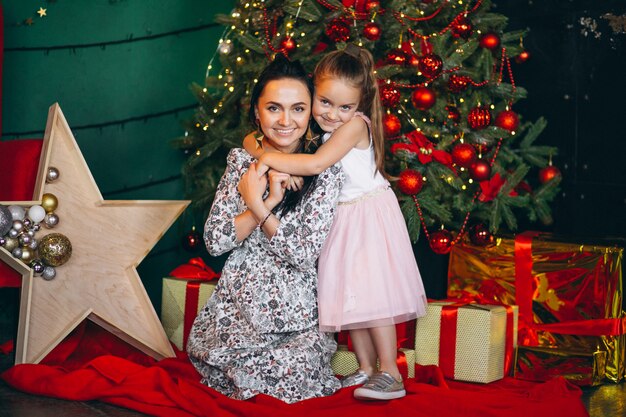 Mother with her little daughter by the Christmas tree