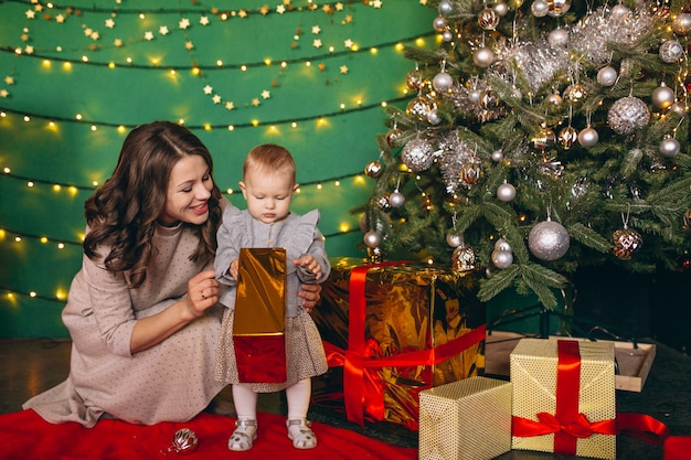 クリスマスツリーで彼女の小さな娘を持つ母