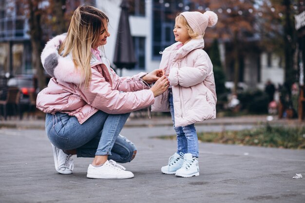 Mother with her little daughter dressed in warm cloth aoutside the street