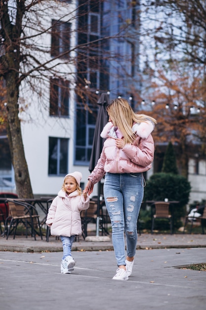 Foto gratuita madre con la sua piccola figlia vestita in panno caldo a lato della strada