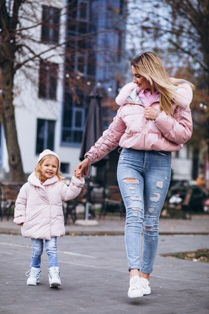 Mother with her little daughter dressed in warm cloth aoutside the street