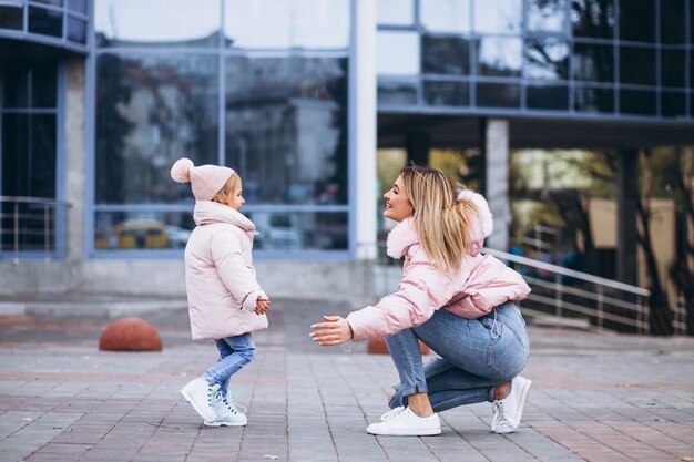 Mother with her little daughter dressed in warm cloth aoutside the street