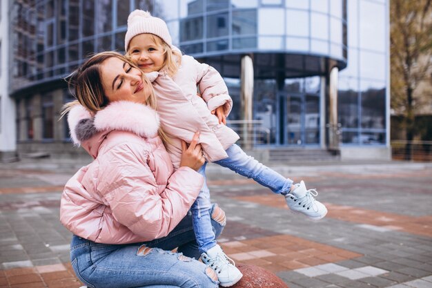 Mother with her little daughter dressed in warm cloth aoutside the street