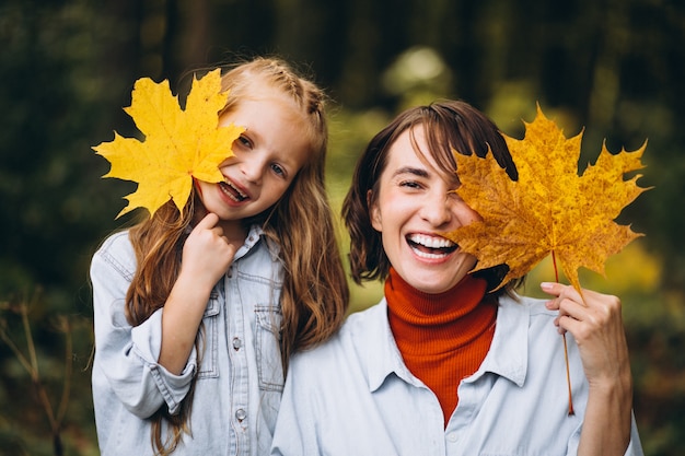 Mother with her little daughter in forest full of golden leaves