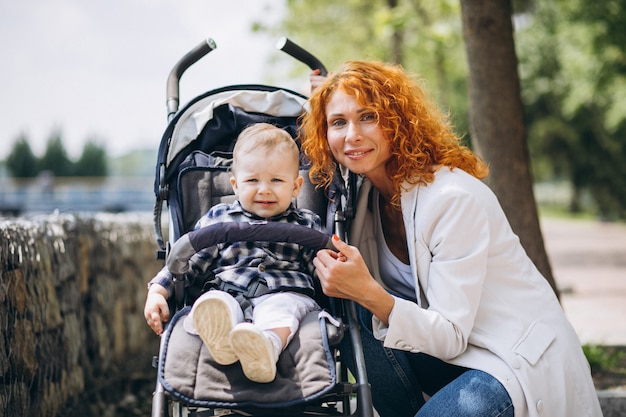 Mother with her little son in a baby carriage in park