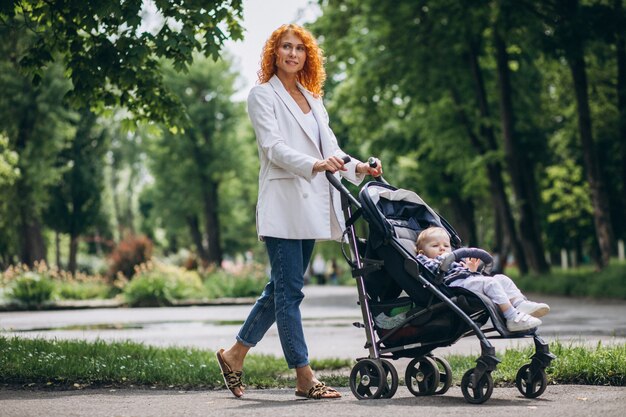 Mother with her little son in a baby carriage in park