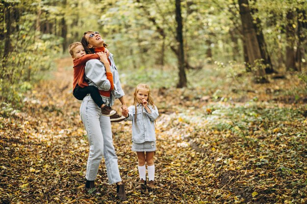 秋の公園で彼女の幼い息子と娘を持つ母