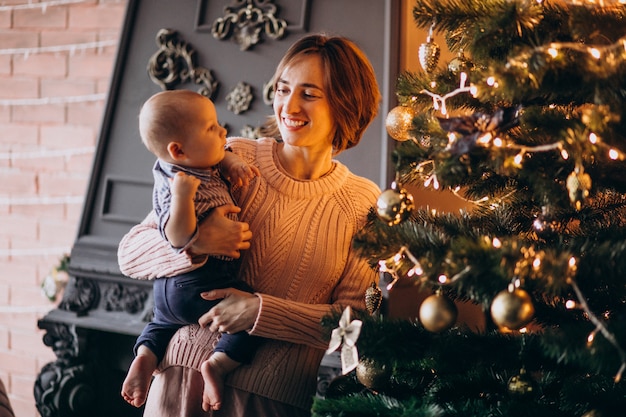 장난감으로 크리스마스 트리를 장식하는 그녀의 작은 아들과 어머니