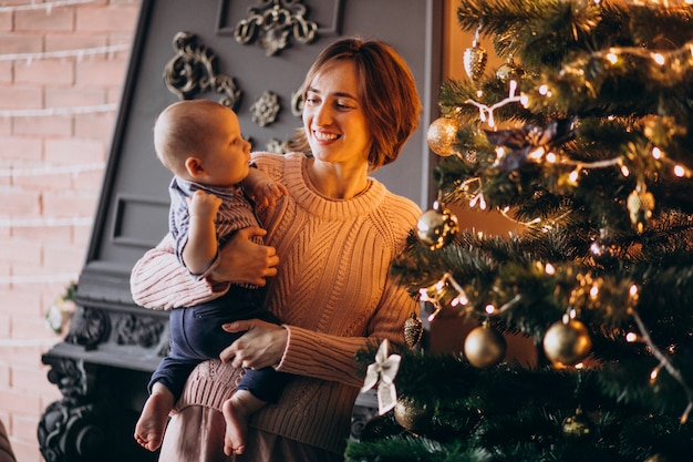 Mother with her little son decorating Christmas tree with toys