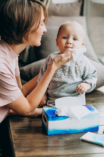 Mother with her little son using napkins for runny nose