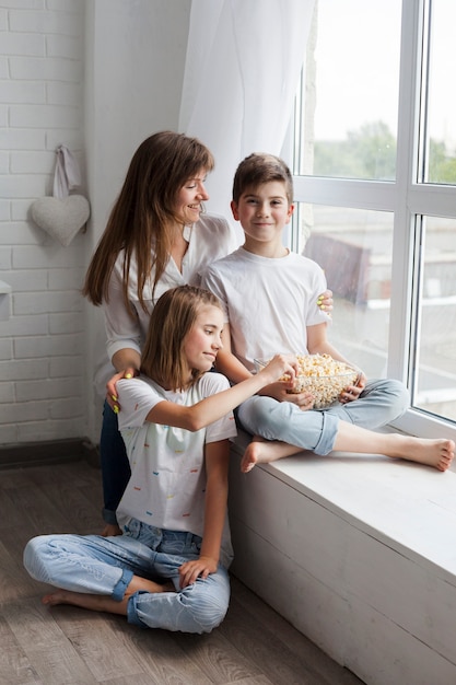 Mother with her son and daughter sitting near window at home