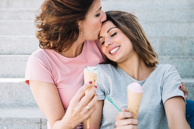 Free photo mother with ice-cream kissing woman