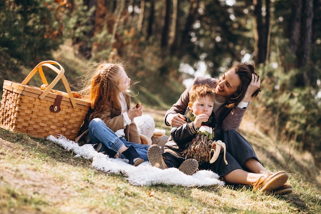 Madre con bambini che hanno picnic nella foresta