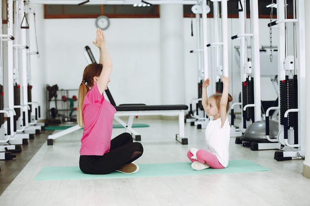 Mother with little daughter are engaged in gymnastics in the gym