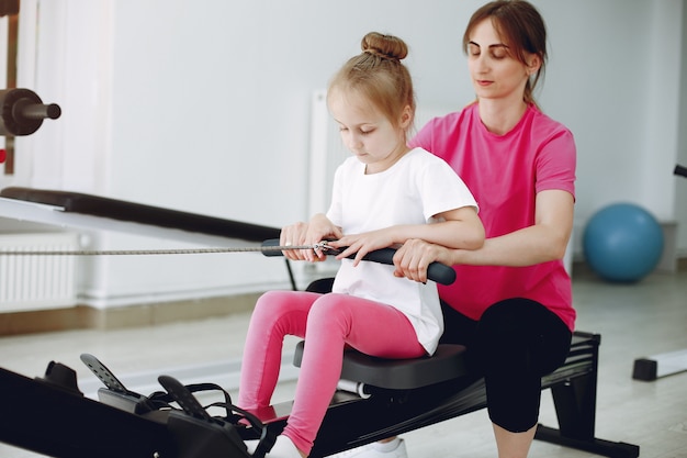 Mother with little daughter are engaged in gymnastics in the gym