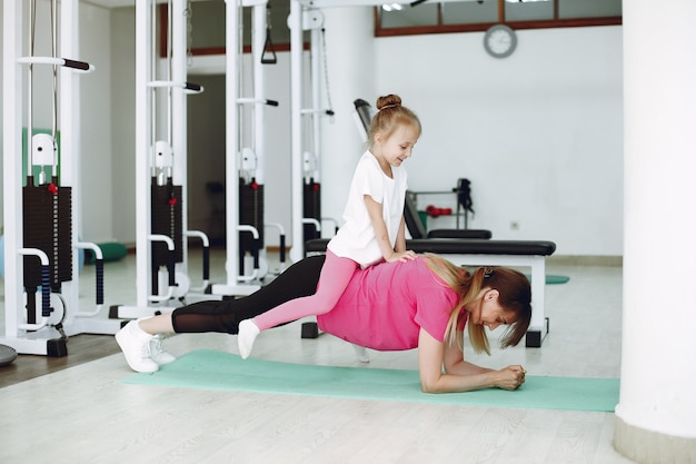 Mother with little daughter are engaged in gymnastics in the gym