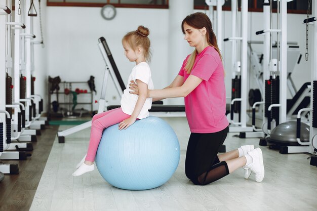 Mother with little daughter are engaged in gymnastics in the gym