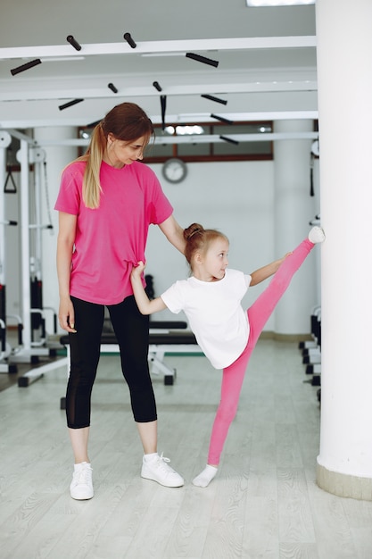 Мама с маленькой дочкой занимаются гимнастикой в спортзале