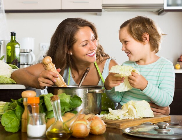 家庭で小さな娘を料理する母親