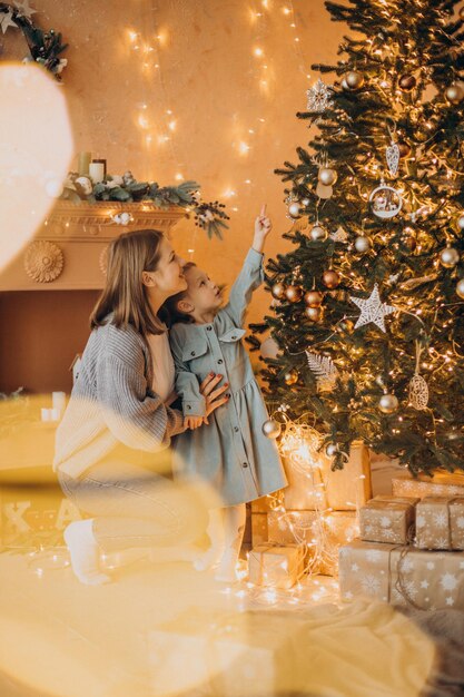 Mother with little daughter decorating christmas tree with toys