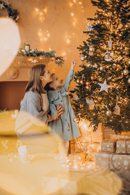 Mother with little daughter decorating christmas tree with toys