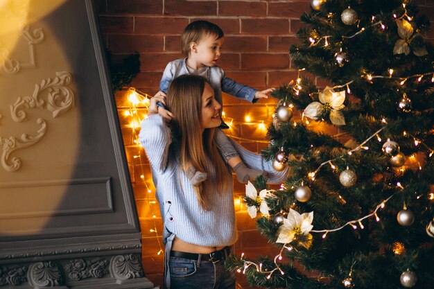 クリスマスツリーを飾る小さな娘を持つ母