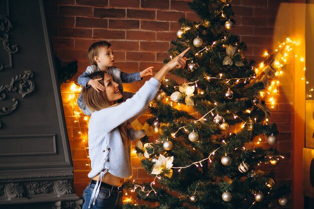 クリスマスツリーを飾る小さな娘を持つ母