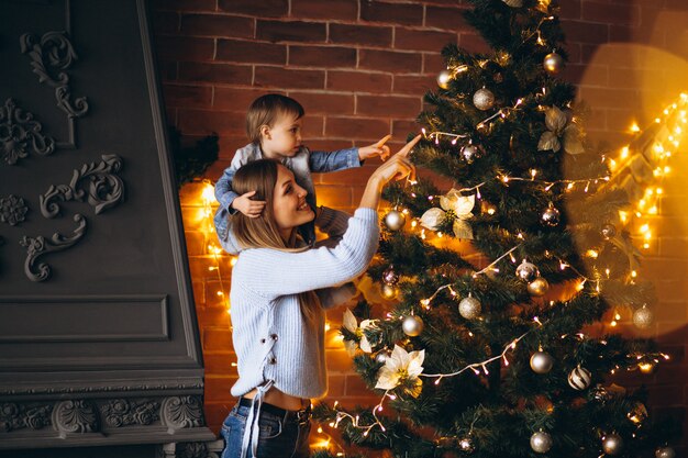 クリスマスツリーを飾る小さな娘を持つ母