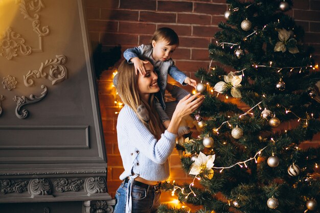 クリスマスツリーを飾る小さな娘を持つ母
