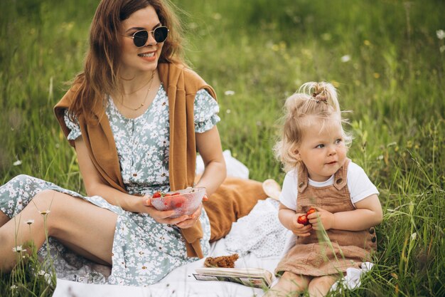 公園でピクニックを持つ小さな娘を持つ母