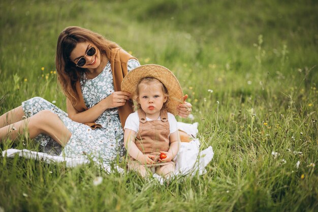 Mother with little daughter having picnic in park