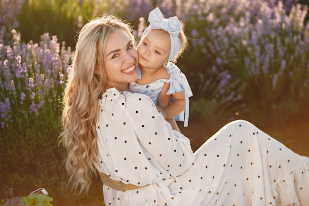 Madre con la piccola figlia sul campo di lavanda. bella donna e bambino sveglio che giocano nel campo del prato. vacanze in famiglia in una giornata estiva.