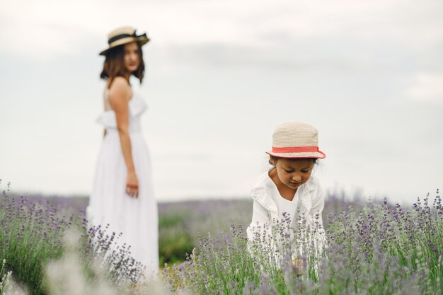 Mother with little daughter on lavender field. Beautiful woman and cute baby playing in meadow field. Family holiday in summer day.