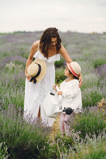 Mother with little daughter on lavender field. Beautiful woman and cute baby playing in meadow field. Family holiday in summer day.