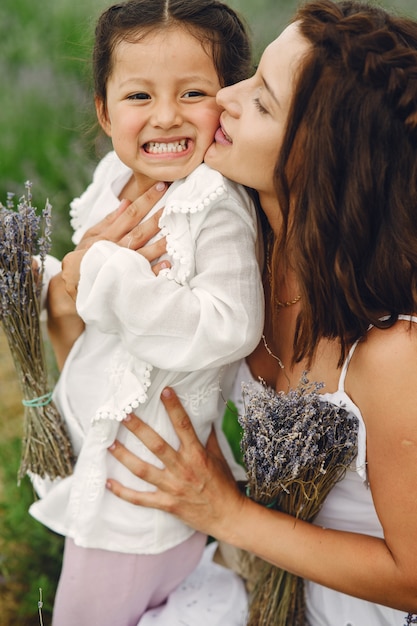 Madre con la piccola figlia sul campo di lavanda. bella donna e bambino sveglio che giocano nel campo del prato. vacanze in famiglia in una giornata estiva.